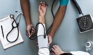 Image is of a woman's arm being examined by a doctor.